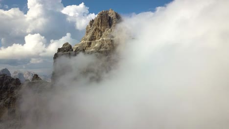 un pico de montaña cubierto por nubes blancas esponjosas, vista aérea de primer plano del parque nacional drei zinnen, monte paterno, dolomiti, italia