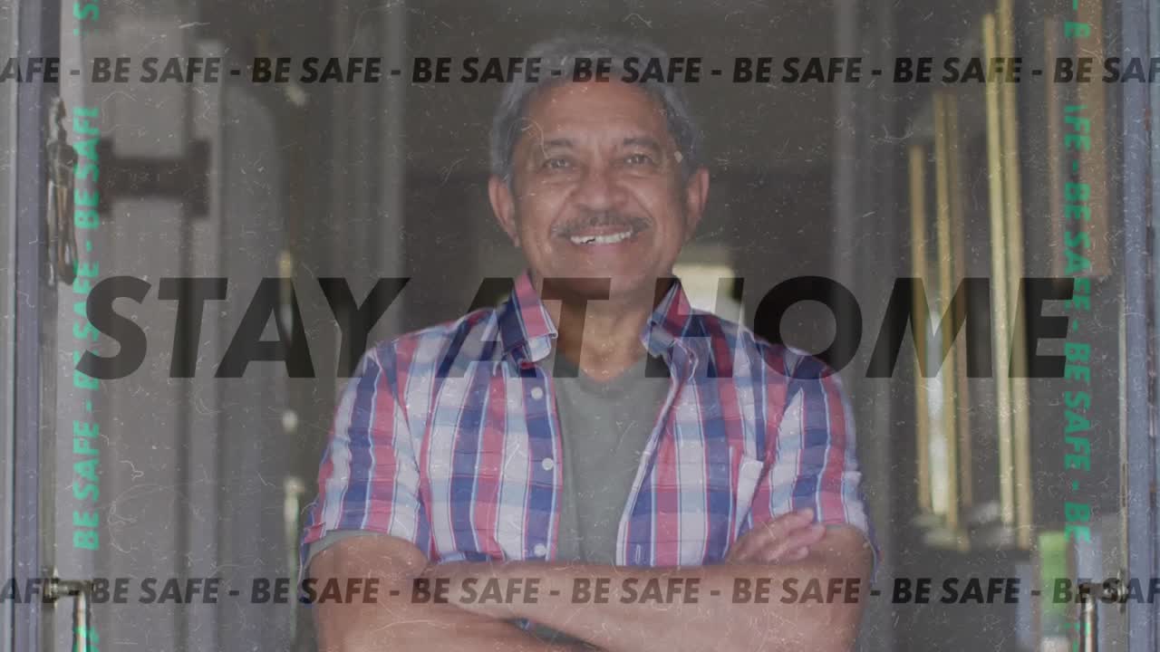 Animation of stay at home be safe text over senior man smiling at home