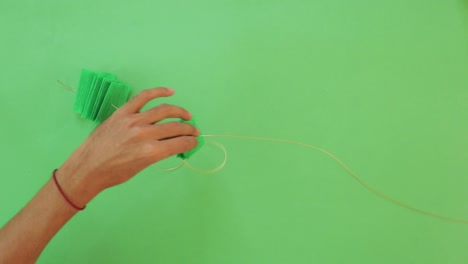 male hands creating handmade mexican crafts and decorations on green table