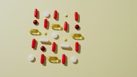 vídeo de una variedad de pastillas y cápsulas dispuestas sobre un fondo amarillo con espacio para copiar.