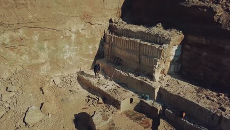 worker is drills stones with using pneumatic tool in the sand quarry. camera motion up. aerial view