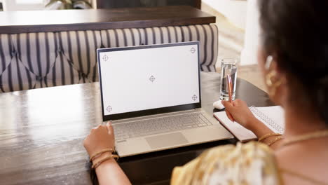 working from home, indian woman using laptop and taking notes at desk, copy space