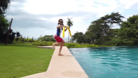 un niño encantador saludando a la cámara mientras corre hacia una piscina con un fideo woggle