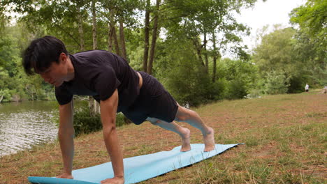 hombre con ropa deportiva haciendo yoga en una alfombra en el bosque junto a un lago o río disfrutando de la paz y la belleza de la naturaleza 1