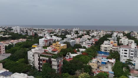 Wide drone view of urban Chennai blending sea, sand, and residential housing