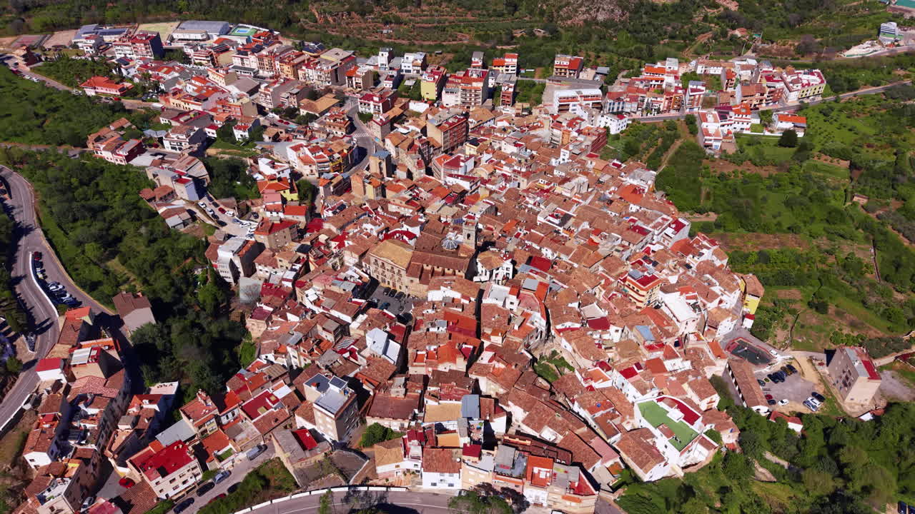 Ovenfra-udsigt over landsbyen Eslida i Castellón-provinsen, Valencia-regionen, Spanien, der viser tætte terrakottatage omgivet af frodige grønne bakker
