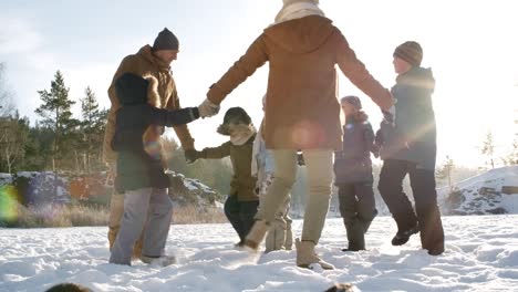 familia haciendo danza en círculo en la nieve