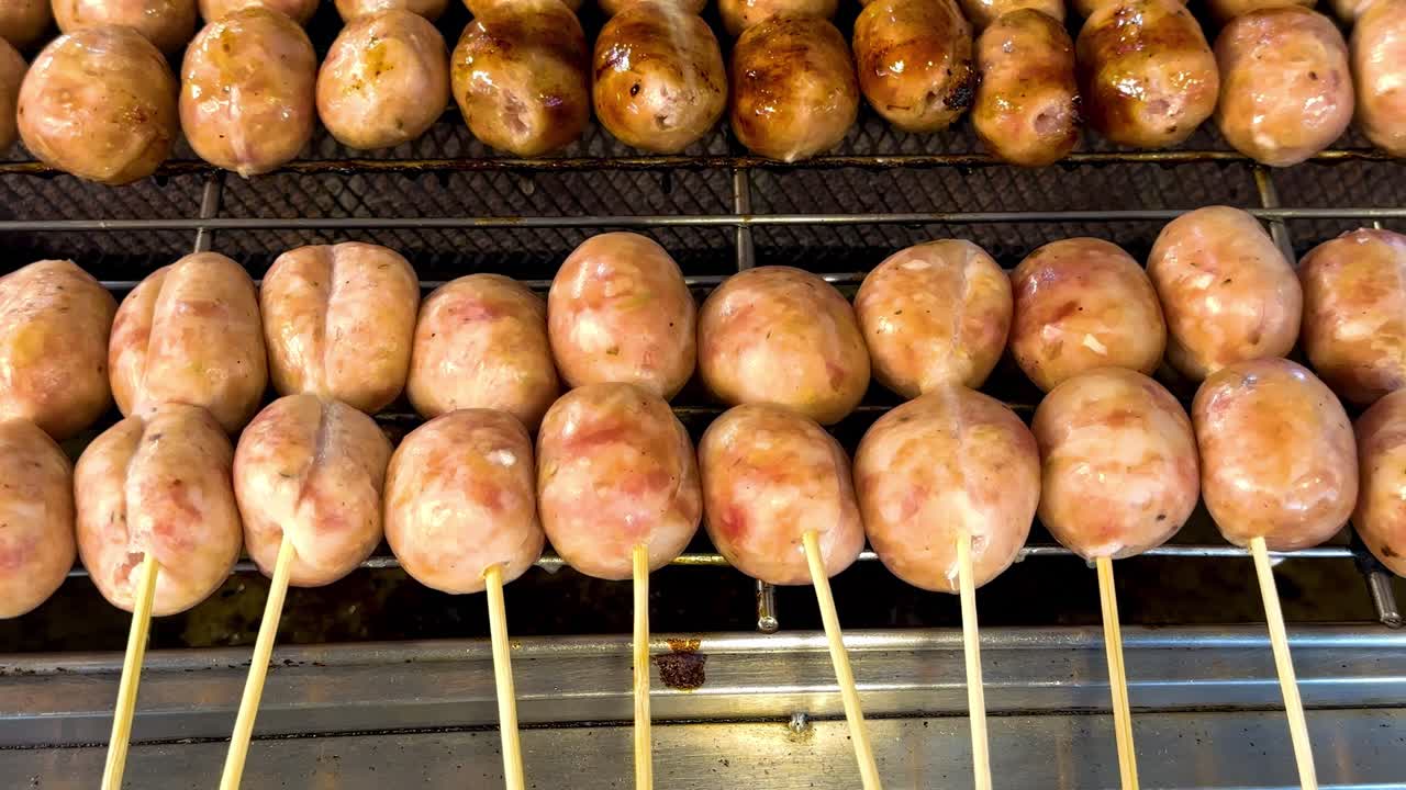 Close-up view of sausages being grilled on skewers over a charcoal grill.