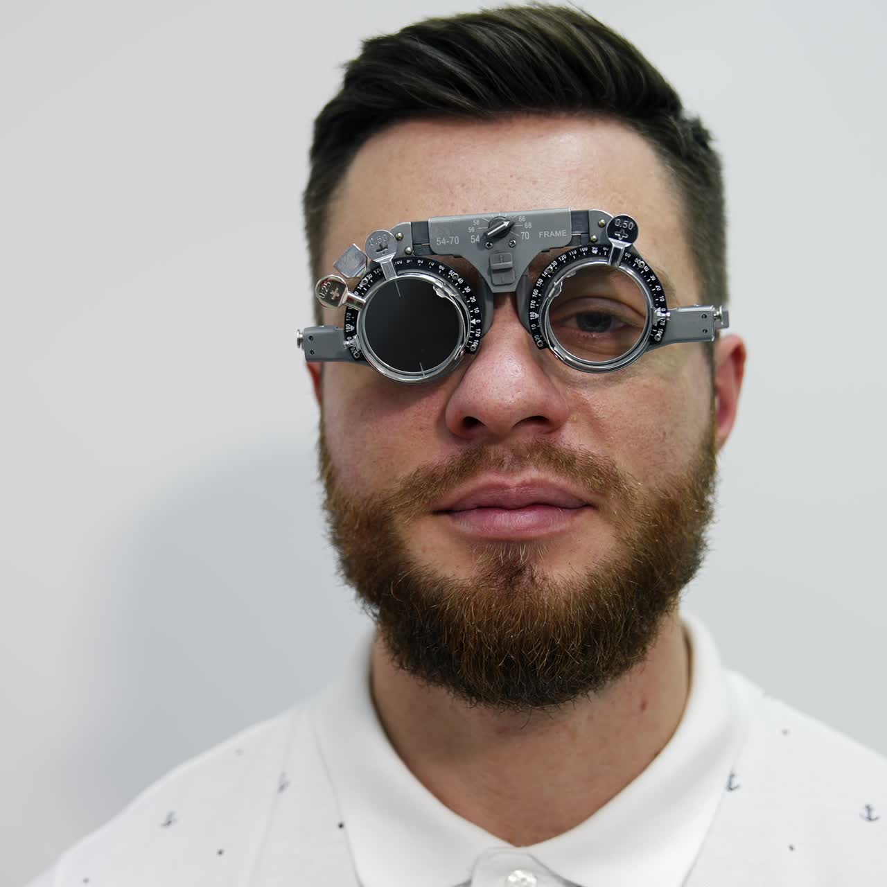 Facial portrait of a man in trial frame. Young handsome bearded man in medical glasses for testing eyes looking on camera. Optical concept