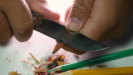 Footage-of-hands-slowly-sharpening-a-pencil-and-some-coloured-pencils-with-a-sharp-knife