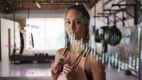 fitness data tracking animation over woman holding jump rope in gym