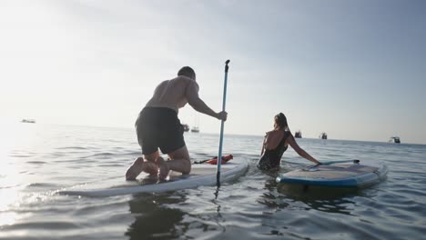 couple paddleboarding in the ocean at sunset