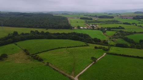 Aerial-drone-shot-panning-green-meadows-and-hills-on-horizon