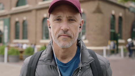 portrait-of-mature-attractive-caucasian-man-puts-on-earphones-listening-to-music-enjoying-urban-city-travel