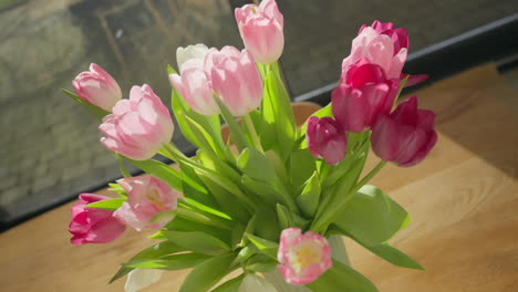 tulipanes vibrantes tomando el sol en una mesa de madera