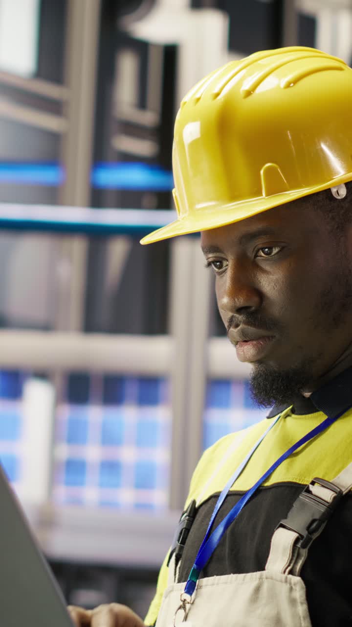 Vertical video Engineer in smart factory does maintenance using laptop software, analyzing data