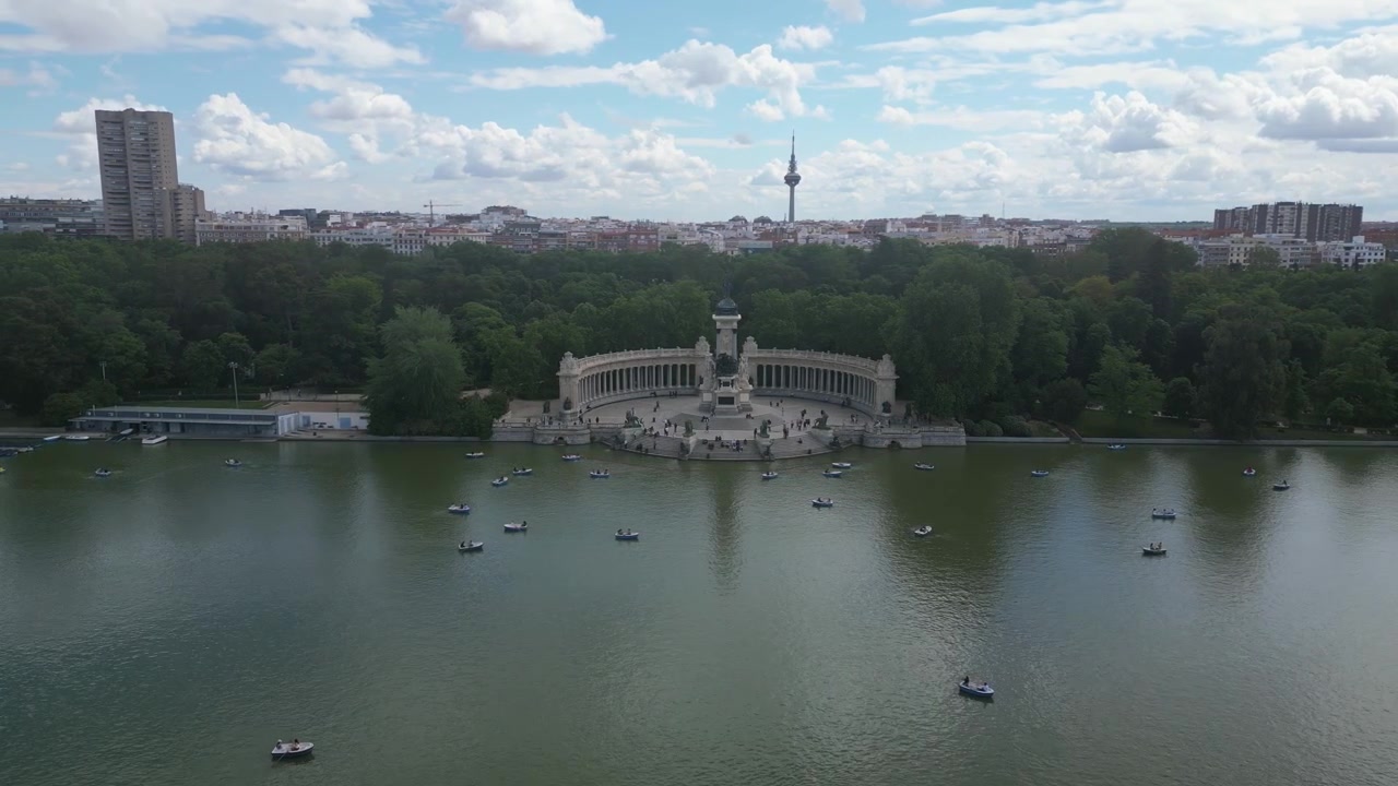 Alfonso XII-monumentet med både på søen i El Retiro Park. Skyfyldt himmel og byens skyline i det fjerne. Velegnet til rejse- og kulturrelevant indhold