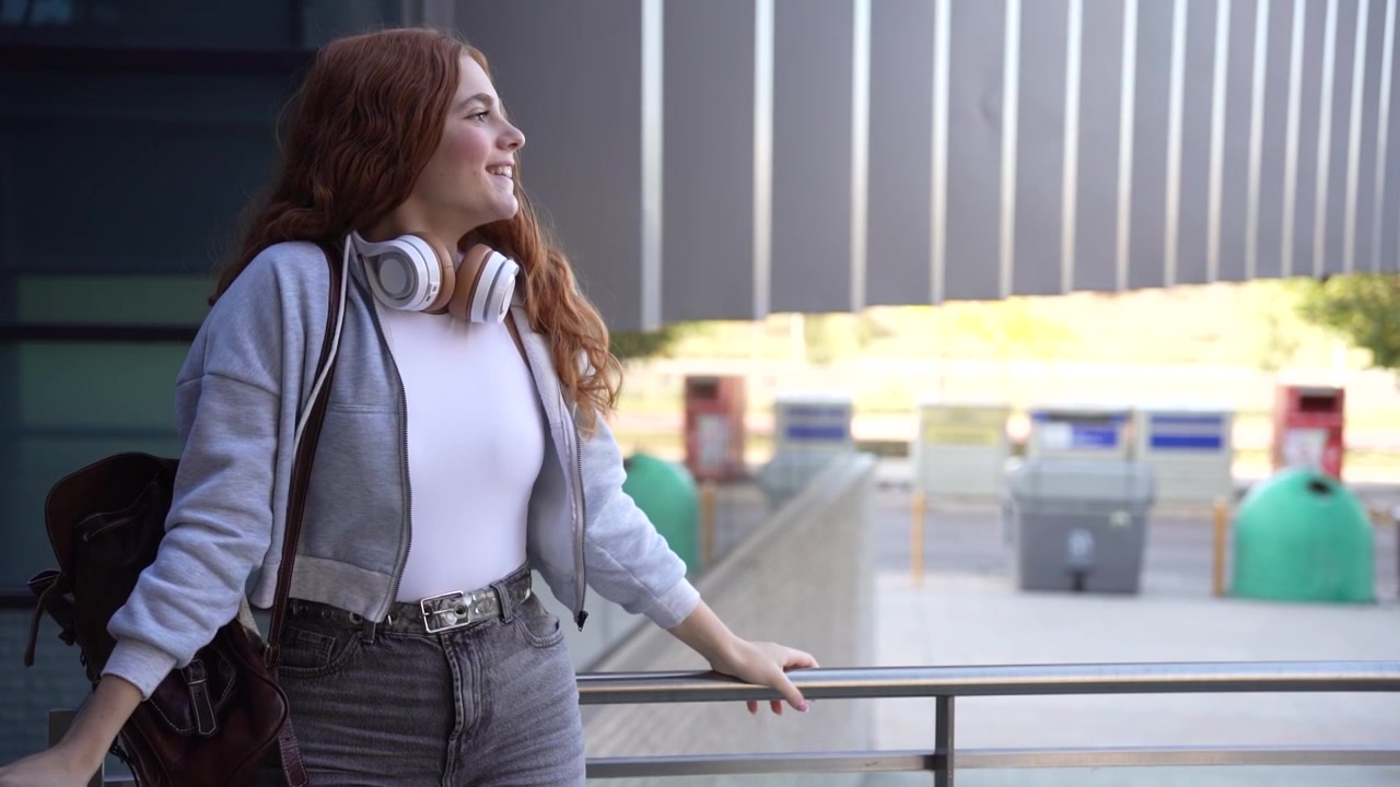 Una giovane donna usa un tablet all'aperto con cuffie alla moda, godendosi l'estate e la tecnologia.