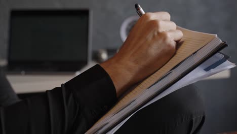 close view of man holds a notebook, writing notes, lyrics, or poems