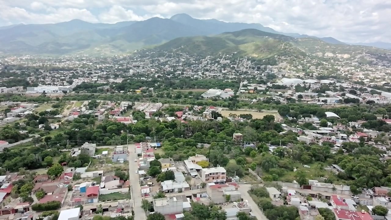 Vista aerea con drone della città di Huatulco che mostra quartieri residenziali, vegetazione lussureggiante e montagne circostanti, evidenziando lo sviluppo urbano e il paesaggio naturale