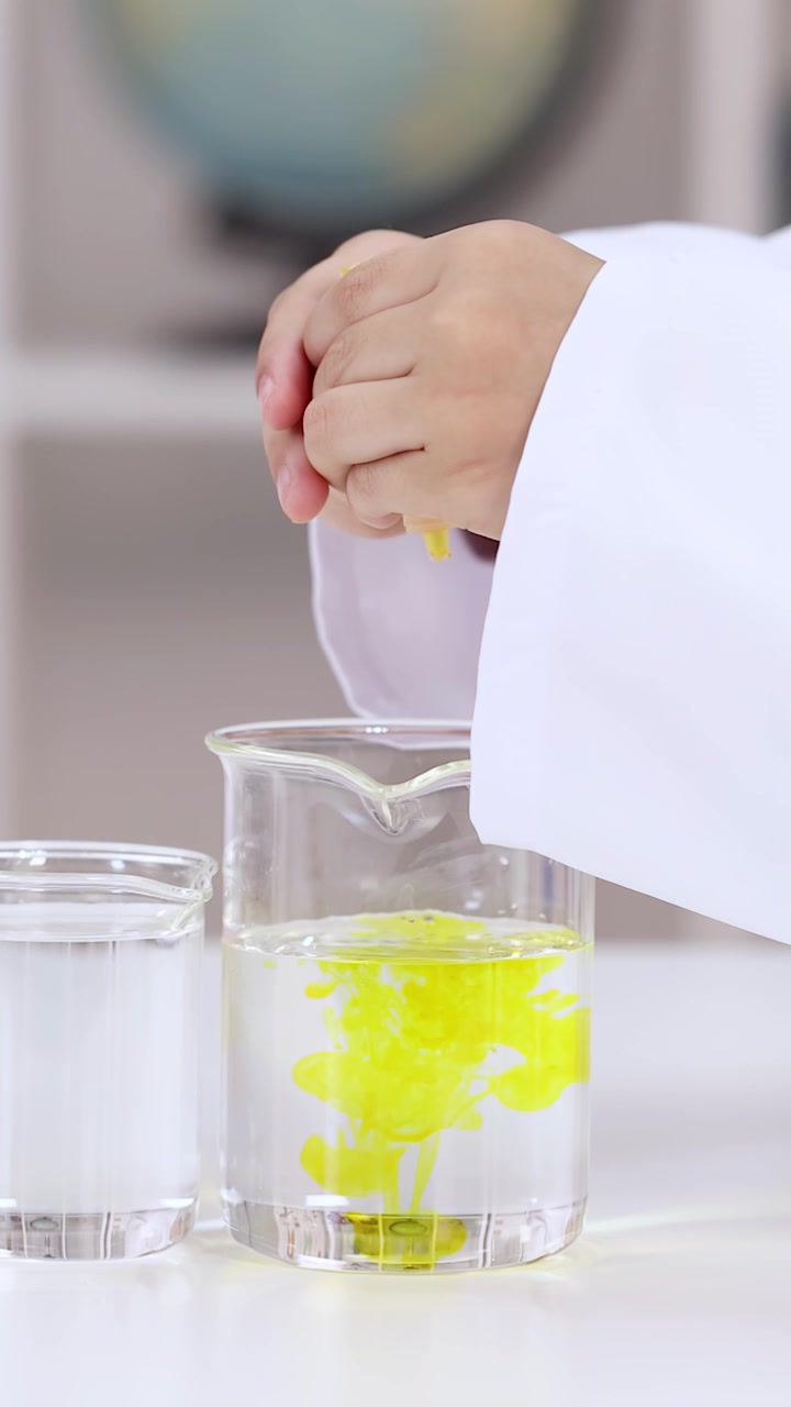 Primo piano di uno studente che esegue un esperimento di chimica con colorante giallo in un laboratorio scolastico