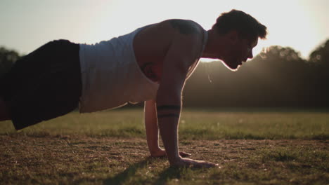 Hombre-Haciendo-Flexiones-En-El-Parque-Bajo-El-Sol-Vespertino