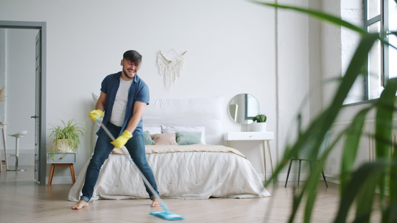 Man Cleaning with a Mop While Singing