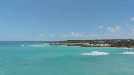 scenic drone flight over ocean near beachfront resort showing golf course and natural shoreline