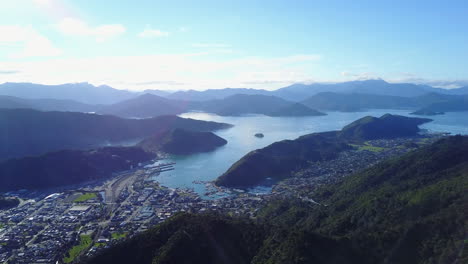 aerial shot of a town, blue ocean, and green forest