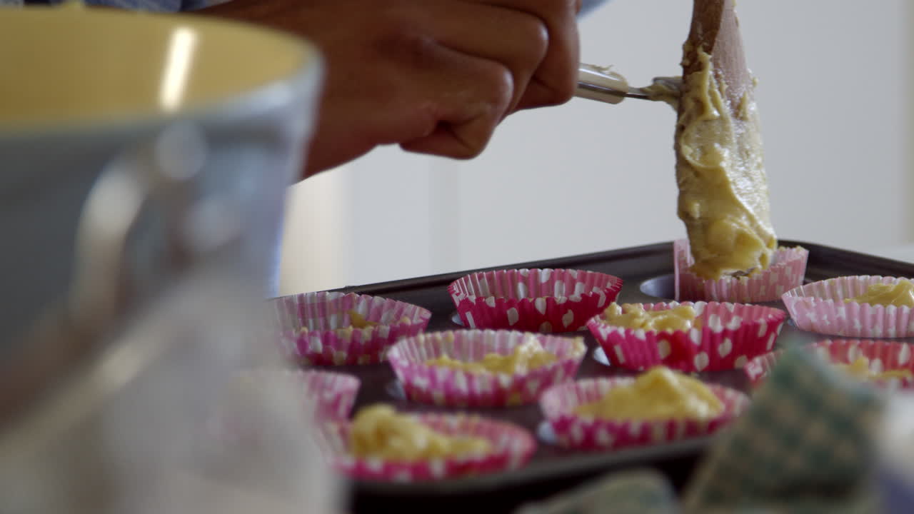 Bambina che mette l'impasto nei pirottini per torte con il padre, ripreso con R3D.