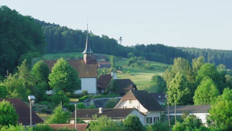 Schwenkaufnahme-Der-Stadt-Melchnau-In-Der-Schweiz-Mit-Blick-Auf-Den-Dichten-Wald,-Der-Die-Stadt-Umgibt