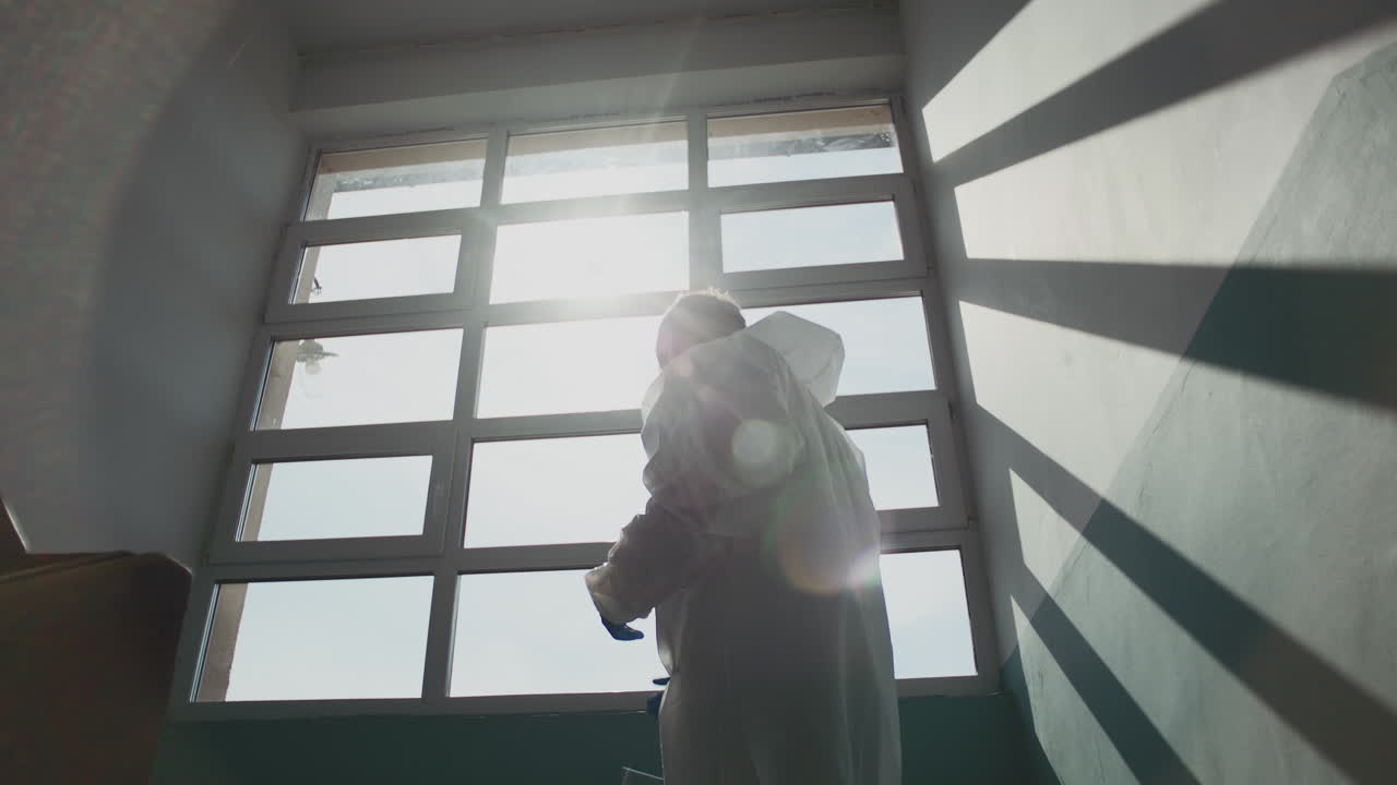 Person in protective suit by a window