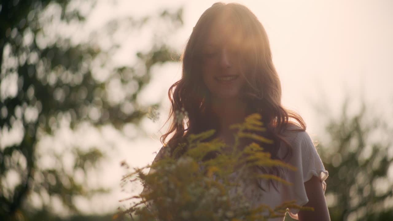 Dreamy girl holding wildflowers at sunset