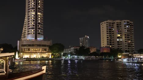 barco navegando a lo largo de un río en una ciudad iluminada por la noche