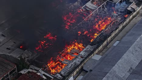 infierno con llamas rojas y calientes devasta el almacén de la fábrica en la zona industrial, aéreo