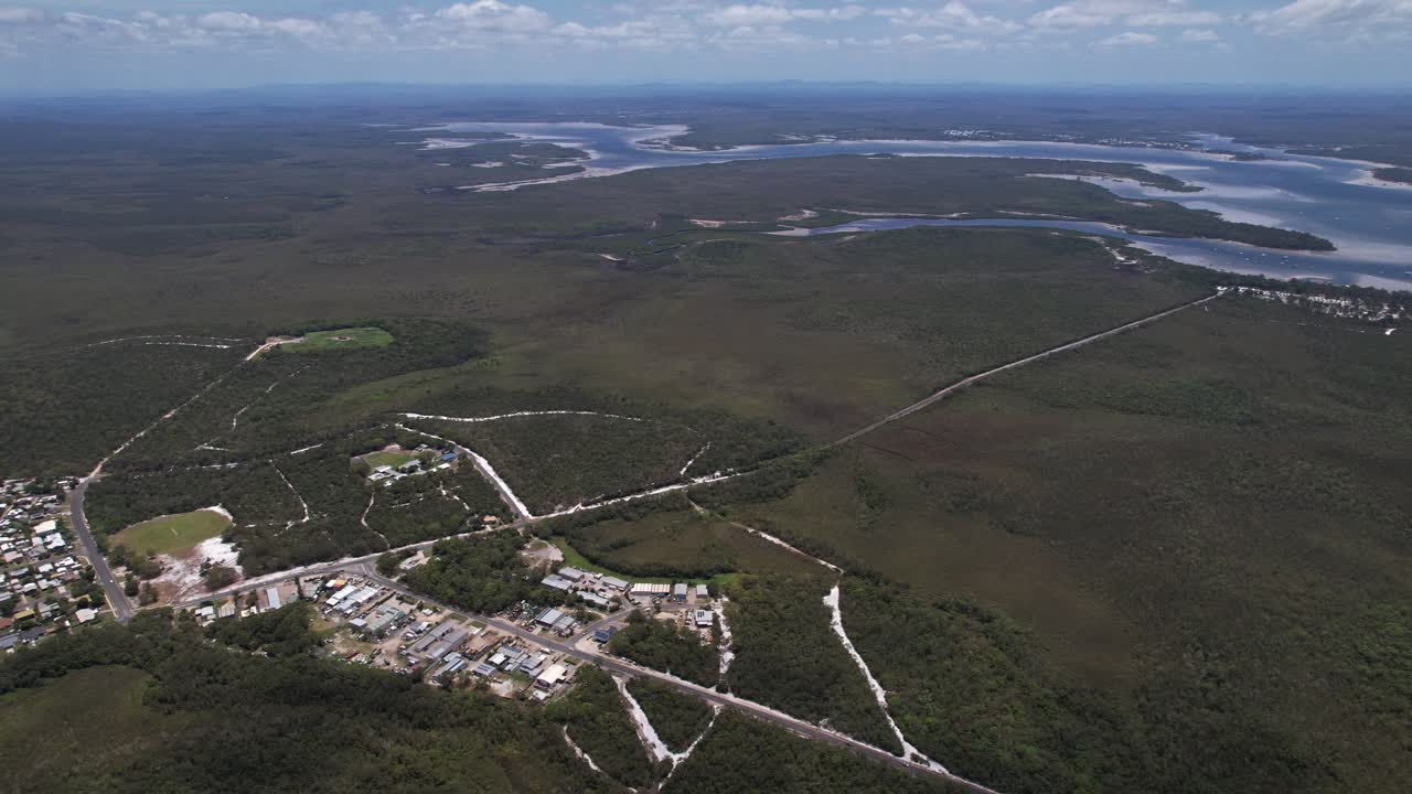 Forested Landscape Of Rainbow Beach With View Of Great Sandy Strait River In Queensland, Australia. aerial panning shot