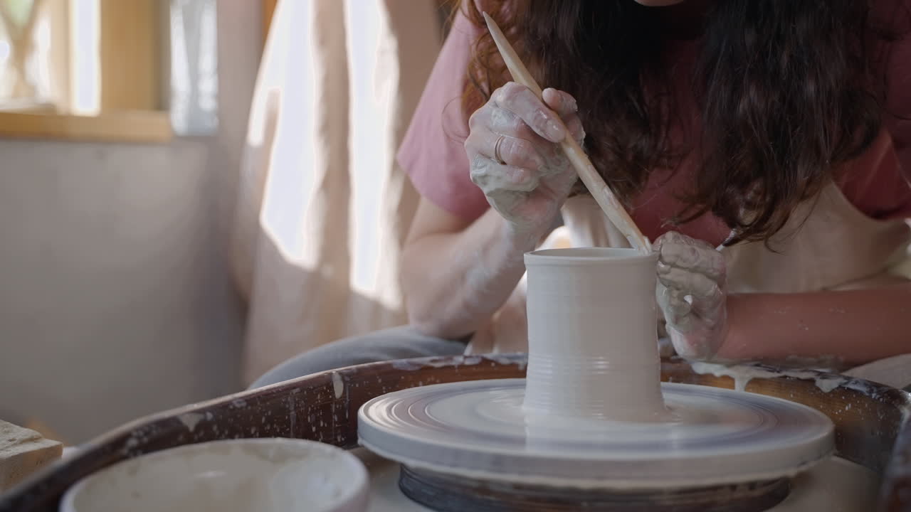 mujer moldeando arcilla en una rueda de cerámica