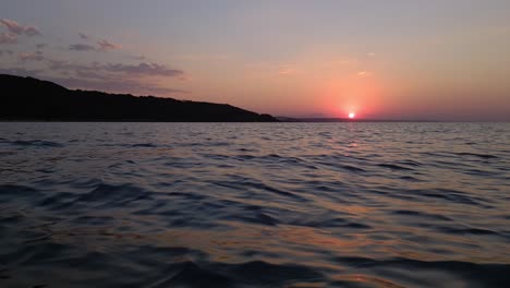 Extreme-low-angle-pov-moving-sideways-on-sea-water-surface-at-sunset