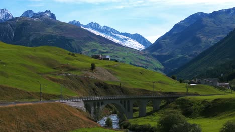 furka pass landscape in switzerland with railway crossing brick bridge under which torrent river flows