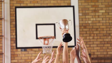 high school kids holding trophy in basketball court