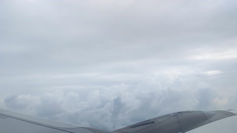 the wing of a passenger plane flying high in the sky with cloud - a cloudy sky