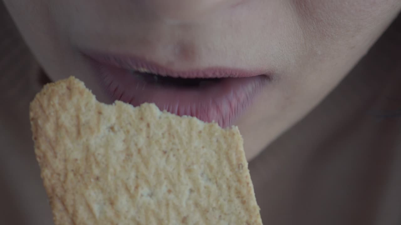 una mujer comiendo una galleta.