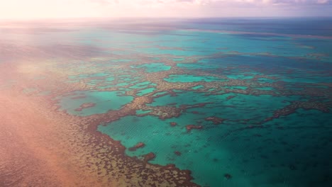 Gran-Barrera-De-Coral-Exterior-Resistente-Laguna-Arrecife-Corazón-Vuelo-Panorámico-Dron-Aéreo-Islas-Whitsundays-Australia-Qld-Parque-Nacional-Soleado-Sereno-Formación-De-Coral-Nubes-Azul-Claro-Aguamarina-Aguas-Del-Océano-Brumoso