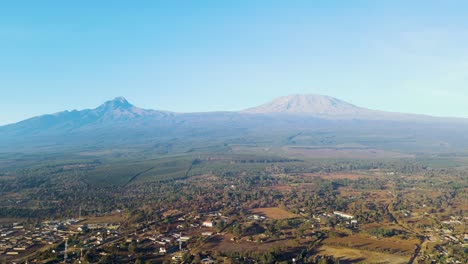 Sunrise--Kenya-landscape-with-a-village,-Kilimanjaro-and-Amboseli-national-park---tracking,-drone-aerial-view