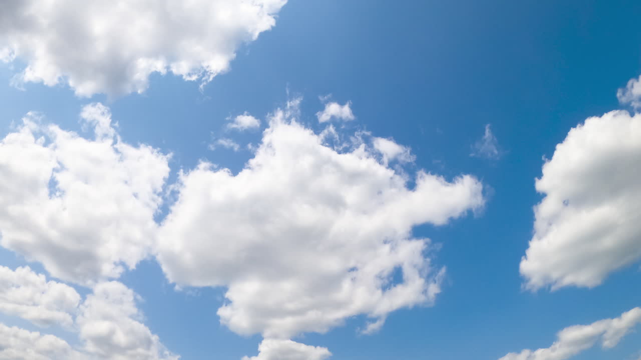 Blue summer sky with fluffy clouds forming. White clouds appear and disappear in the atmosphere. Low angle view. Timelapse.