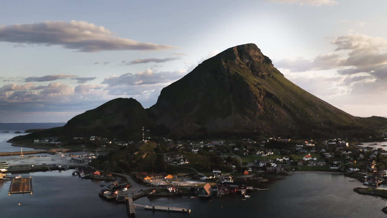 Aerial drone shot flying towards the Island of Lovund with the summit of Lovundfjellet towering over the village. Lovund, Norway