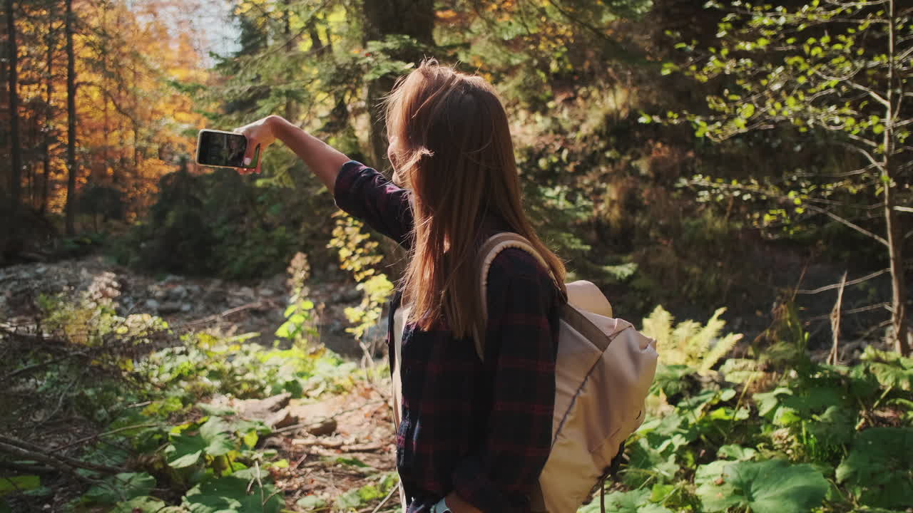 mujer tomando una selfie en el bosque de otoño