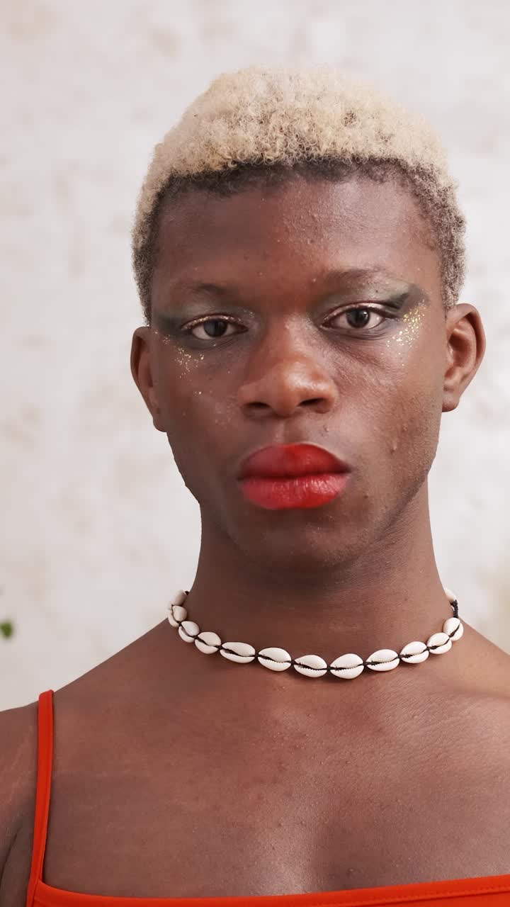 Portrait of a person with dramatic glitter makeup and a shell necklace