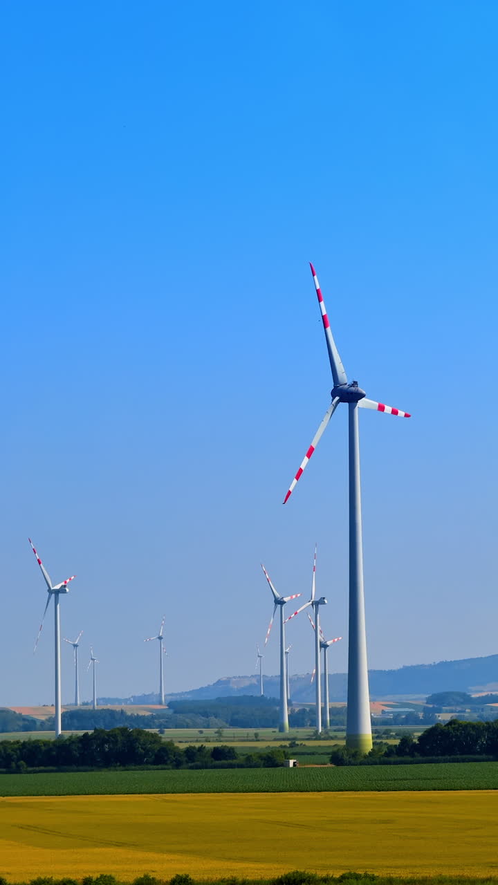 Wind turbines on farmland. Wind turbines spin over green fields under a clear blue sky, generating renewable energy