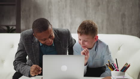 niño mira video a través de la computadora portátil y se ríe con el profesor de inglés